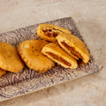Achari mathi broken open to show the spiced achari filling