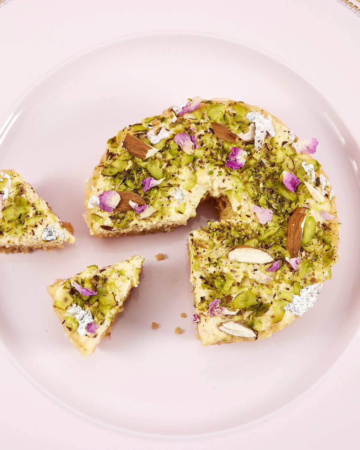 Ghevar topped with pistachio, almond and rose petals, cut into slices