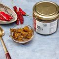 Pure Desi chilli pickle in a bowl with fresh and dried red chillies beside the jar