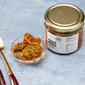 Thick-cut mango pickle pieces in spiced oil beside the Pure Desi jar