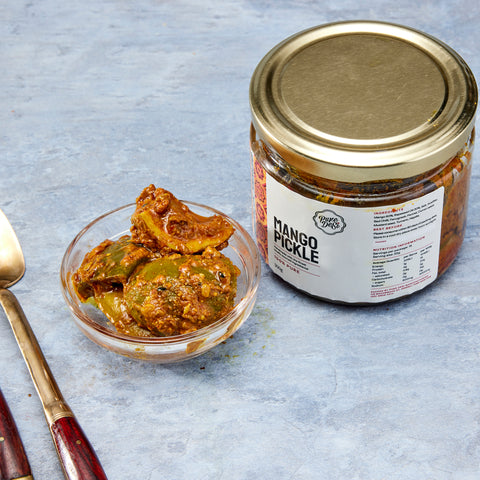 Thick-cut mango pickle pieces in spiced oil beside the Pure Desi jar