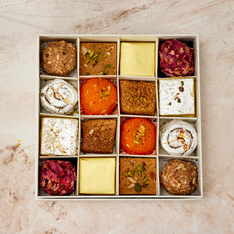 Top view of the Bring India Home box: Kesar Motichoor Burfi, Gond Ladoo, Danedar Burfi, gold-wrapped Channa Burfi, Rose Badaam Ladoo, Kaju Jalebi, Milk Cake and Sangam Burfi